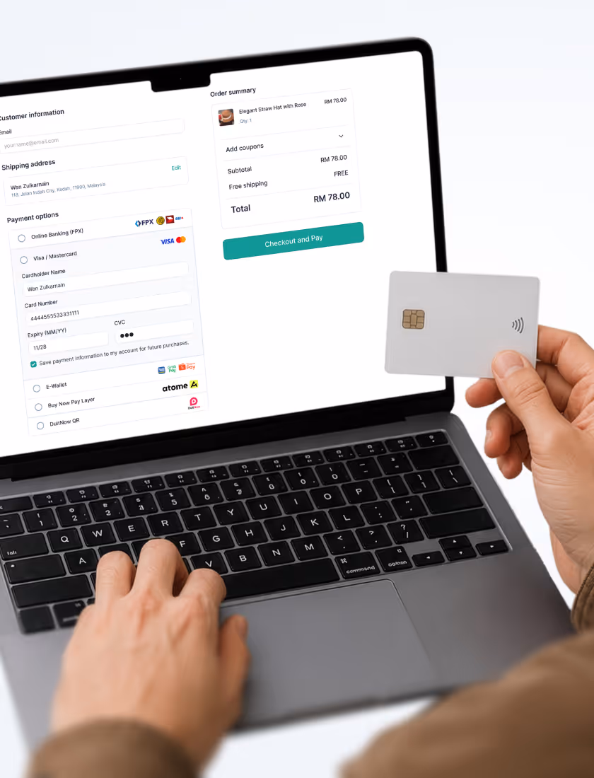Person holding contactless card while typing on laptop displaying online payment checkout screen.